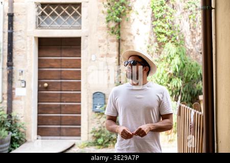 Mann, der in einer historischen Gasse steht und eine Sonnenbrille trägt Stockfoto