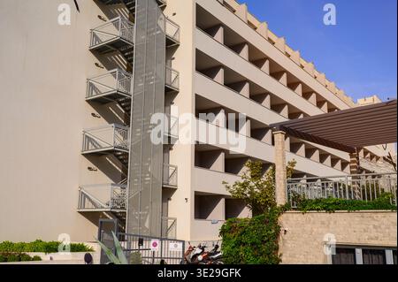 Außenansicht einer mehrstöckigen Wohnung unter klarem blauem Himmel. Grünes Laub unterstreicht die moderne Konstruktion. Konzept einer umweltfreundlichen Stadtplanung Stockfoto