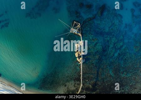 Aus der Vogelperspektive auf einen Trabucco, der hoch über dem türkisfarbenen Meer in der Nähe von Punta Aderci steht, ein starker Kontrast zur felsigen Küste, Vasto, Abruzzen, Italien. Stockfoto