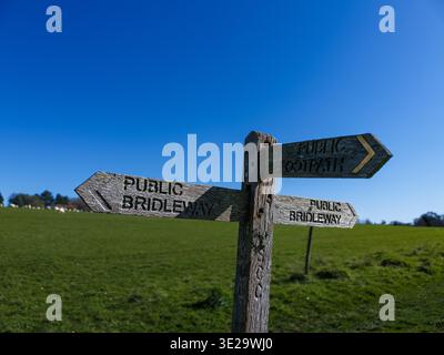 Verwitterte hölzerne Wegweiser zu öffentlichen Fußwegen und Brückenwegen inmitten üppiger grüner Weiden in der Nähe von Pulborough in den South Downs, West Sussex, Großbritannien Stockfoto