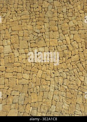 Hochauflösende gelbe Steinwand-Textur mit unregelmäßigen Blöcken, nützlich als nahtloser Hintergrund für Architektur, Bau, Mauerwerk, rustikales Design und Projekte mit natürlichem Gesteinsmuster. Stockfoto