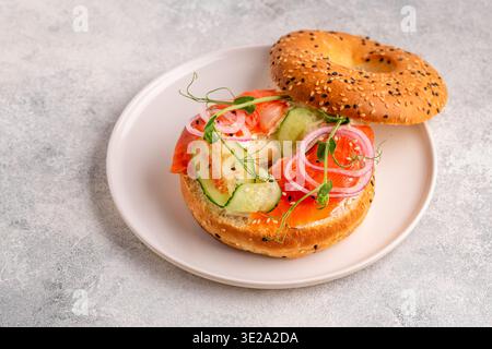 Bagel und Lachs-Lachs mit Frischkäse, Gurken, Zwiebeln und Microgreens. Stockfoto