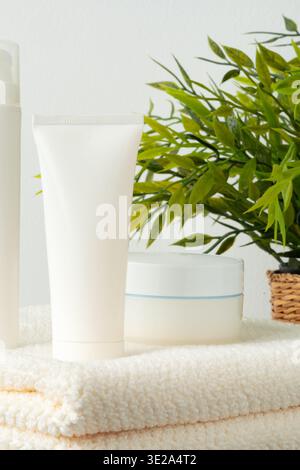 Hautpflegeprodukte auf Handtüchern in der Nähe einer Pflanzenanzeige im Badezimmer Stockfoto