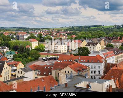 Panoramablick auf Döbeln: Historische Altstadt mit roten Ziegeldächern, Bushaltestelle und grüne sächsische Landschaft in Deutschland Stockfoto