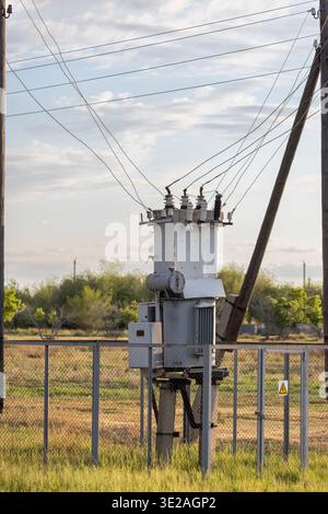 Einen Hochspannungstransformator und die dazugehörigen Drähte an einem Holzmast Stockfoto