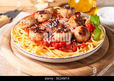 Ein Teller mit klassischen Spaghetti, garniert mit gebräunten Fleischbällchen und reichhaltiger Tomatensauce auf einem leichten Keramikgericht. Stockfoto