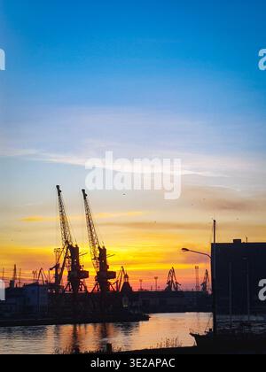 Industriehafenkrane Silhouetten beim goldenen Sonnenuntergang im Hafen Stockfoto