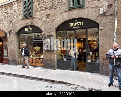 Giusti Modena. Florenz, Italien. Die Fassade des historischen Gebäudes zeigt handwerkliche Balsamico-Produkte und Fässer. Kunden, die draußen stehen. Stockfoto