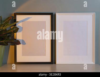 Leere Frames für Bildmaterial oder Druck auf grünem Hintergrund. Wohnzimmereinrichtung mit schwarz-weißen Fotorahmen. Skandinav Stockfoto
