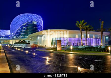 Besucher genießen die moderne Architektur des W Abu Dhabi Yas Island Hotels bei Nacht. Das Hotel verfügt über leuchtende Lichter und Palmen in der Umgebung. Stockfoto
