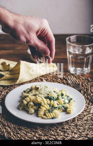Essen, Fusilli-Pasta mit Spinat und Ricotta garniert mit geriebenem Parmesankäse auf weißer Platte Stockfoto