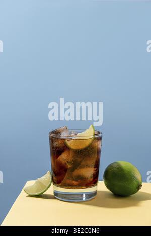 Kuba Libre Alkohol Cocktail mit Limettenscheibe auf blauem Hintergrund. Whiskey-Cola-Cocktail Stockfoto