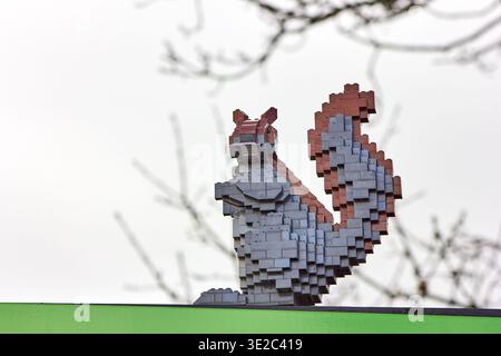 Eine detailgetreue Skulptur eines Eichhörnchens, die vollständig aus LEGO-Ziegeln gefertigt wurde, steht vor einem hellen, bewölkten Himmel. Die dreidimensionale... Stockfoto