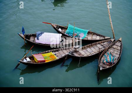 Keraniganj, Bangladesch - 23. September 2022: Blick auf kleine Holzboote, die sich zusammengeschlossen haben, deren bunte Verkleidungen sich auf das plätschernde Wasser reflektieren Stockfoto