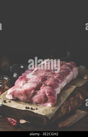 Essen, rohe Schweinelende auf Schneidebrett mit verschiedenen Gewürzen Stockfoto