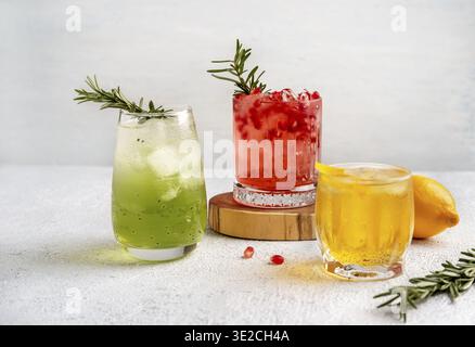 Drei farbenfrohe Sommercocktails in Gläsern auf einem weißen Tisch. Auswahl an frischen Sommergetränken. Rote Sangria-Cocktails, Orangenpunsch-Cocktails, margarita Stockfoto