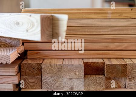 Gestapelte Holzdielen und quadratische Holzstücke mit natürlicher Holzmaserung und verschiedenen Texturen, die Rohstoffe für Baugewerbe und Autos darstellen Stockfoto