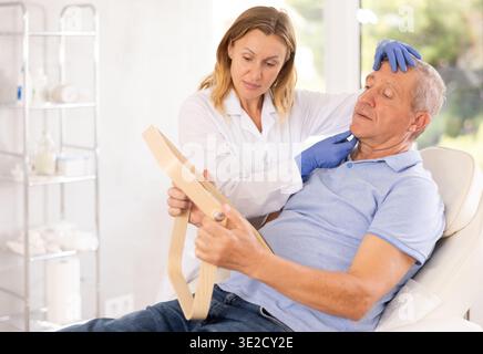 Kosmetologin berät Seniorenmann vor Gesichtsbehandlungen Stockfoto