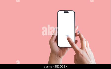 Weibliche Hände halten Mobiltelefon mit leerem weißen Bildschirm über rosafarbenem Hintergrund, Social-Media-Marketing-Konzept Stockfoto