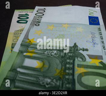Makroansicht gestapelter Euro-Banknoten auf dunklem Hintergrund mit 100- und 50-Euro-Banknoten mit Symbolen der Europäischen Union, ideal für Sparfinanzierung und Währungsreserven Stockfoto