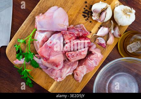 Roh geschnittenes Kaninchen, das auf einem Holzschneidebrett mit Gewürzen liegt Stockfoto