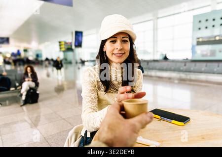 Frau genießt Kaffeepause im geschäftigen Flughafenterminal Stockfoto