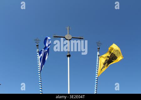 Griechische Fahnen und orthodoxes Kreuz August 2024 nationale und religiöse Symbole vor blauem Himmel Stockfoto
