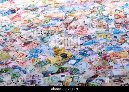 Viele Banknoten unterschiedlicher Währung. Eine große Menge von zufälligen Geldrechnungen aus der Nähe. Währungsumtausch-Konzept Stockfoto