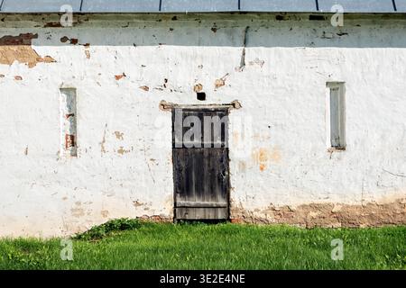 Alte Holztür in einer Ziegelwand mit weißem Putz. Aus den Türen der World of the World-Serie. Stockfoto