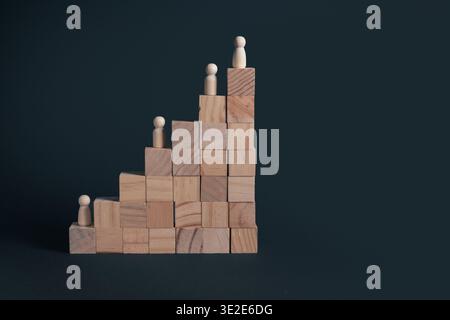 Holzpfeilfiguren stehen auf gestapelten Holzblöcken, die eine Stufenstruktur bilden, die Karriereentwicklung, Hierarchieebenen, Beförderung und Professi darstellt Stockfoto