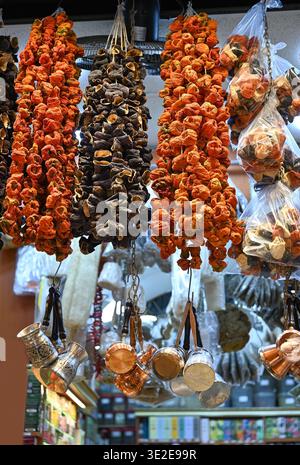 An einem Marktstand hängen Haufen getrockneter Paprika und Auberginen sowie eine Auswahl an türkischen Kupferkaffeekannen aus Silber und Kupfer. Stockfoto