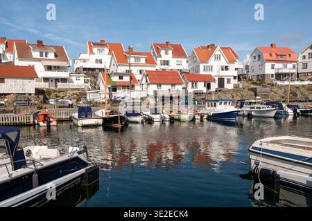 Weiße Holzhäuser mit roten Dächern und Booten im Hafen der Insel Åstol, Bohuslän, Westküste Schwedens Stockfoto