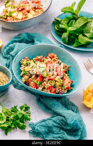 Farbenfroher Couscous-Salat mit Tomaten und Gurke in rustikaler Schüssel, garniert mit frischer Minze Stockfoto