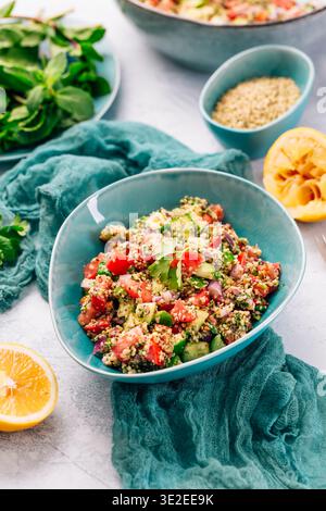 Farbenfroher Couscous-Salat mit Tomaten und Gurke in rustikaler Schüssel, garniert mit frischer Minze Stockfoto
