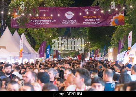 Beim Jerewan Wine Days Festival versammelt sich ein lebhaftes Abendpublikum entlang der Straße unter dem Event-Banner und den warmen Lichtern. Stockfoto