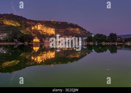 Der Bundi Palace und die Gebäude am See werden in der Abenddämmerung beleuchtet und ihre Lichter reflektieren das dunkle Wasser des Nawal Sagar Lake. Stockfoto