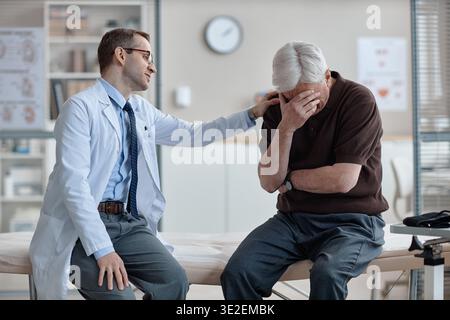 Kaukasischer Urologe tröstet den notleidenden älteren kaukasischen Mann in der Klinik Stockfoto