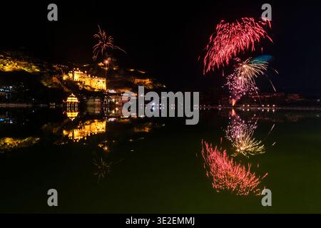 Ein Feuerwerk erleuchtet den Nachthimmel über dem Nawal Sagar Lake in Bundi, während sich der beleuchtete Garh Palace im ruhigen Wasser spiegelt. Stockfoto