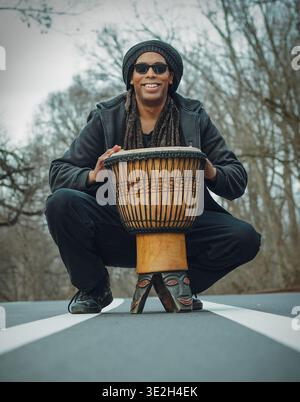 Ein Mann mit Dreadlocks spielt einen Djembe auf dem Highway Stockfoto