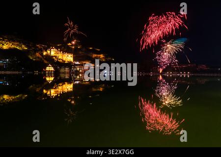 Ein Feuerwerk erleuchtet den Nachthimmel über dem Nawal Sagar Lake in Bundi, während sich der beleuchtete Garh Palace im ruhigen Wasser spiegelt. Bundi Rajasthan Indi Stockfoto