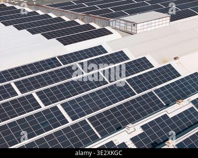 Luftansicht von Industriegebäuden mit Solarpaneelen auf Dächern zur Förderung der Energieeffizienz und nachhaltiger Logistikpraktiken. Stockfoto