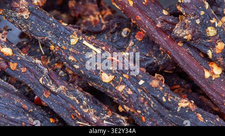 Makronaht von Biltong mit detaillierter Textur und Chili-Gewürz. Traditioneller südafrikanischer Snack aus getrocknetem Fleisch, ideal für Essenshintergründe und Tex Stockfoto