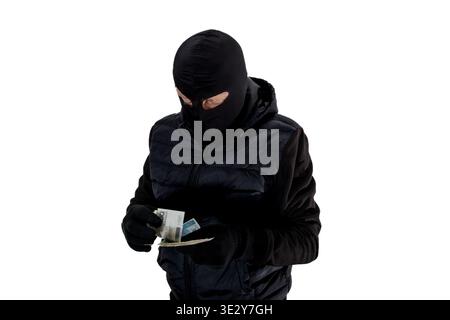 Ein Dieb in schwarz gekleidet zählt Geld nach dem Diebstahl, Geld in den Händen eines Terroristen, der mit einer schwarzen Sturmhaube verkleidet ist, ein glücklicher Dieb zählt Geld an Stockfoto