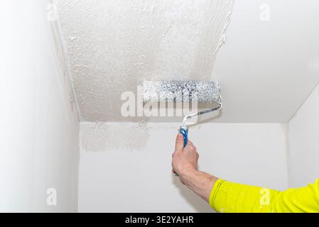 Arbeiter, der während der Renovierung eine dicke Schicht Polymerputz auf eine Innendecke aufträgt Stockfoto