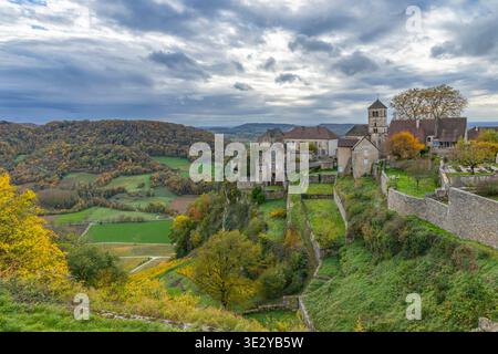 Französisches Dorf auf einem Hügel mit Weinbergen und Herbstbäumen in der Jura-Weinregion Stockfoto