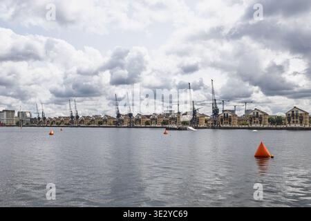 Historische Kräne entlang der Uferpromenade der Londoner Docklands unter Wolken. London, UK, 29. Juni 2023 Stockfoto