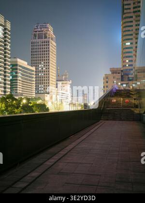 Wuhan, China - 8. März 2025: Ein erhöhter Fußgängerweg mit Blick auf moderne Wolkenkratzer und städtische Infrastruktur. Das Bild zeigt beleuchtet offic Stockfoto