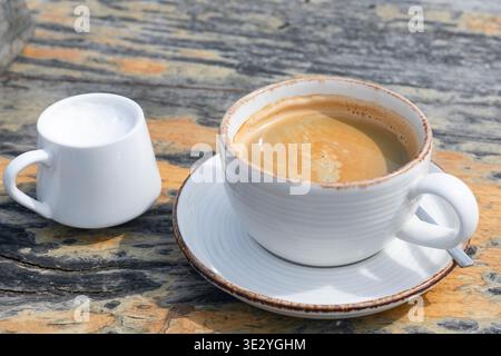 Tasse Kaffee mit Milch auf rustikalem Holztisch Stockfoto