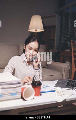 Erschöpfte weibliche Angestellte, die während der Überstunden Burnout erlitten hat. Eine müde Profi-Frau unter Druck mit Kopfschmerzen. Stockfoto