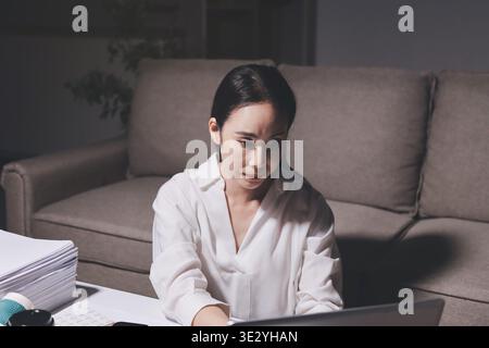 Erschöpfte weibliche Angestellte, die während der Überstunden Burnout erlitten hat. Eine müde Profi-Frau unter Druck mit Kopfschmerzen. Stockfoto